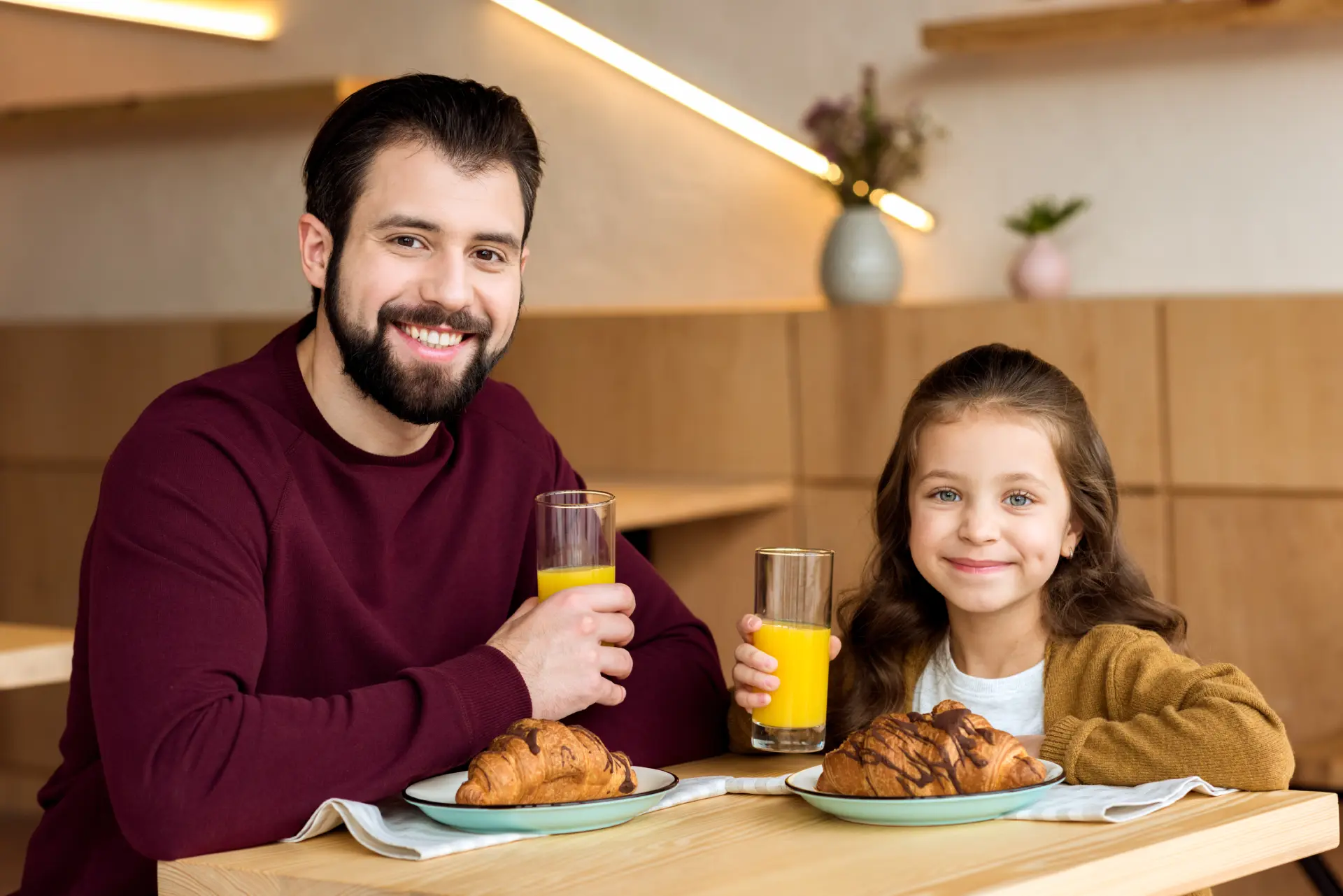 Hombre con hija desayunando sonrientes